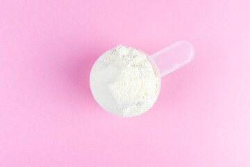 Vanilla protein powder scoop on pink background. Female sport supplements, weight loss powder, plant based, pea powder, organic casein isolate