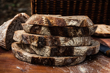 stack of bread slices cut from rustic round loaf artisan decorated with scoring and baked loaf of bread