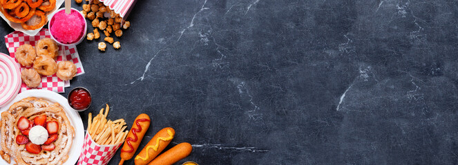 Carnival theme food corner double on a dark background. Overhead view with copy space. Summer fair concept. Corn dogs, funnel cake and snacks.