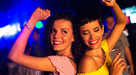 Two happy young girls dancing on the party in the night club