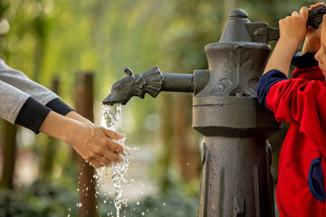 Boy washes his hand under the faucet in park