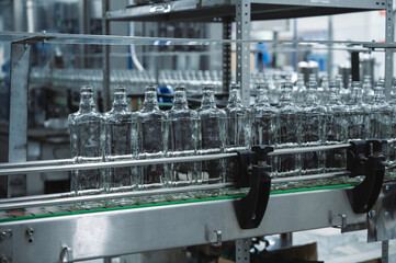 Production line transports empty glass bottles for alcohol