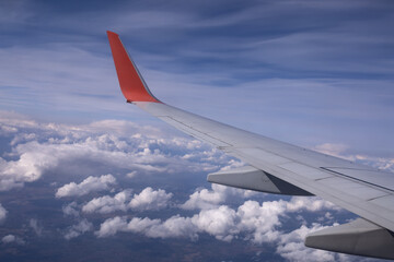 the wing of a flying aircraft against the background of clouds