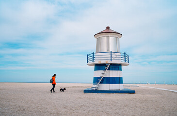 Man and french bulldog on the beach by lighthouse