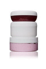 Obraz premium set of three white, red, pink plastic cosmetic jars for face cream on white isolated background with reflection 