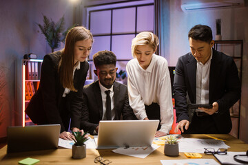 African American leader typing on laptop, discussing project with diverse employees team, writing creative ideas, tasks. Multiethnic colleagues discussing new project plan at meeting