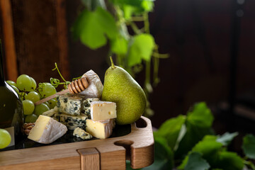 Green ripe pear and brie cheese with honey and crackers. Green grapes.