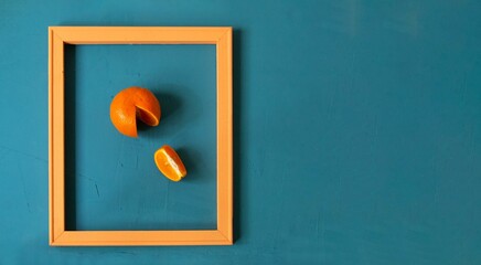 Pop art style food. A modern creative concept of a fruit diet. Tangerine in a frame on a sea-green surface.
