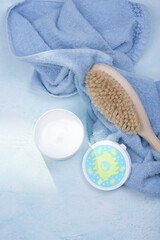 Body creams and brush for body massage on a blue background
