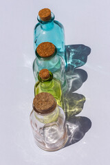  Pequeñas botellas de vidrio, de colores  y con tapones, con su propia sombra