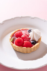 Tartlet with fresh berries and cream for pink background in hard light