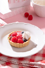Tartlet with fresh berries and cream for pink background in hard light