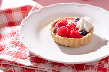 Tartlet with fresh berries and cream for pink background in hard light