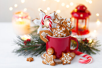 Fototapeta na wymiar Christmas composition with gingerbread cookies, candy cane and marshmallow in a red mug. Cozy home atmosphere, delicious sweet holiday dessert. Traditional spices: cinnamon, anise, cardamom