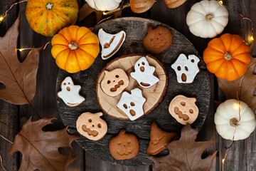 Homemade halloween holiday treats for kids. Gingerbread cookies on wooden board, decorated with pumpkins and autumn leaves. Top view