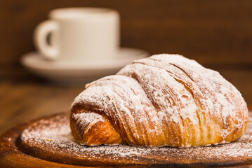 Croissant close up on wooden table and coffee cup copy space.