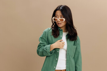 Happy enjoyed Korean young woman in khaki green shirt stylish eyewear looks aside posing isolated...
