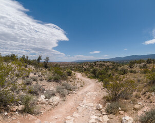 Rocky hiking path in the desert with a blue sky split by incoming clouds.
