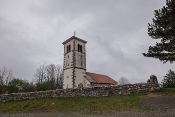 Fototapeta premium Church in silentabor, a small hill above Pivka, Slovenia on a cloudy rainy day. Istrian style church on a top of a hill.