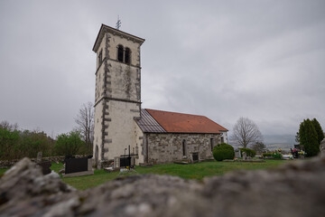 Naklejka premium Church in silentabor, a small hill above Pivka, Slovenia on a cloudy rainy day. Istrian style church on a top of a hill.