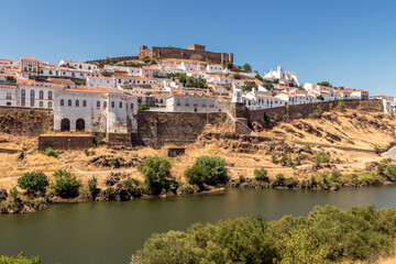 Fototapeta na wymiar View of the village of Mértola in Portugal, with the Guadiana river in the foreground, on a sunny day in summer.
