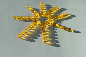 Sun from vitamin d capsules. Sunshine vitamin. Capsules are laid out in the shape of the sun on a blue background