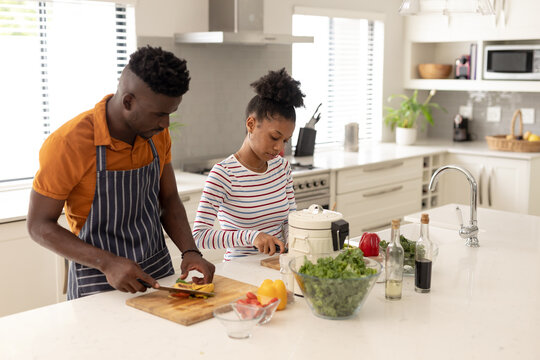 African american young boyfriend with young girlfriend preparing food on kitchen island at home