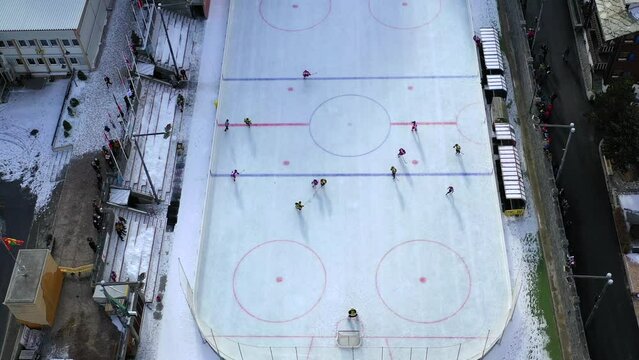 Aerial drone footage from Zermatt, Switzerland.  A game of ice hockey is being played in the middle of the city, on a sunny day.  