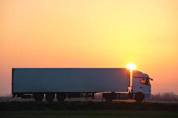 Semi-truck with cargo trailer driving on highway hauling goods in evening. Delivery transportation...