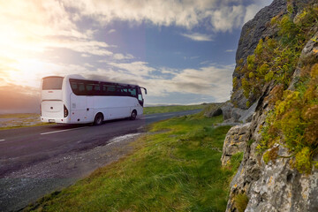White bus passing mountain. Beautiful cloudy sky in the background. Tourism industry. West of...