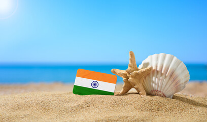 Tropical beach with seashells and India flag. The concept of a paradise vacation on the beaches of India. - obrazy, fototapety, plakaty