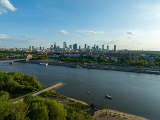 widok z lotu ptaka na centrum Warszawy, panorama miasta, wieżowce i rzekę Wisła, wiosna, zielone drzewa i niebieskie niebo