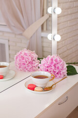 
Client place in hairdressing beauty salon with cup of tea, macaroons and flower