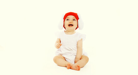 Portrait of laughing baby on the floor wearing red winter knitted hat on white background
