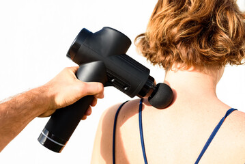 Hand holding a massage gun to apply deep therapeutic percussion massage to painful muscle and relax...