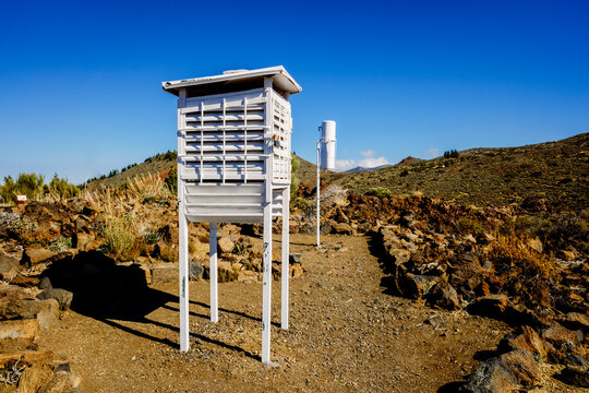 Climate measurement devices at a weather station on white wooden towers on a mountain.