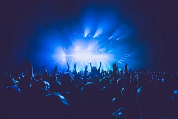 Foto auf Alu-Dibond A crowded concert hall with scene stage lights in blue tones, rock show performance, with people silhouette, on dance floor air during a concert festival © tsuguliev