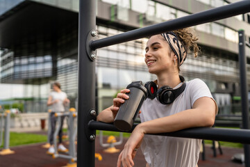 One caucasian woman taking a brake during outdoor training in the park outdoor gym resting on the...