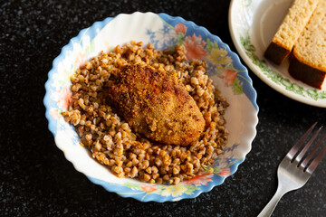 Fototapeta na wymiar Traditional Ukrainian dish - lunch bowl with buckwheat porridge and fried cutlet. Healthy dinner