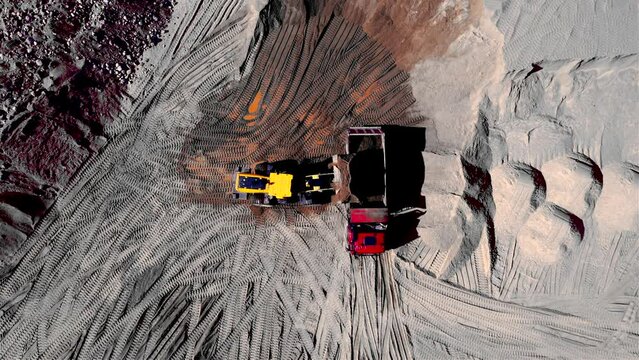 Front end loader on earthworks in quarry. Wheel loader load sand and gravel in dump truck in open pit. Heavy machinery in opencast. Mining truck transports crushed stones and sand from open-pit