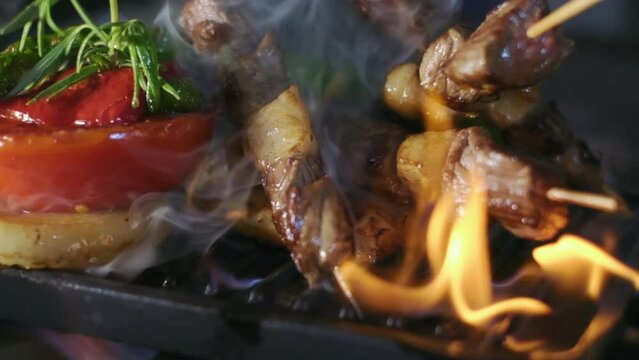 Cooking flambe style dish at professional restaurant kitchen. Slow motion food shot. meat skewers with vegetables are fried with flame. Slow motion 4K. Turkish cuisine