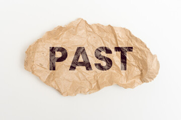 Crumpled craft paper fragment with the inscription: PAST. The concept of old memories and lost...
