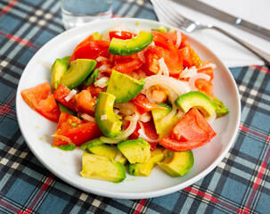 Healthy vegetable salad of sliced fresh tomatoes, avocado and onion with olive oil