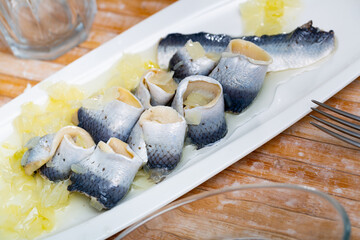 Delicious herring fillet with onion and sunflower oil, laid out on a plate. Close-up image