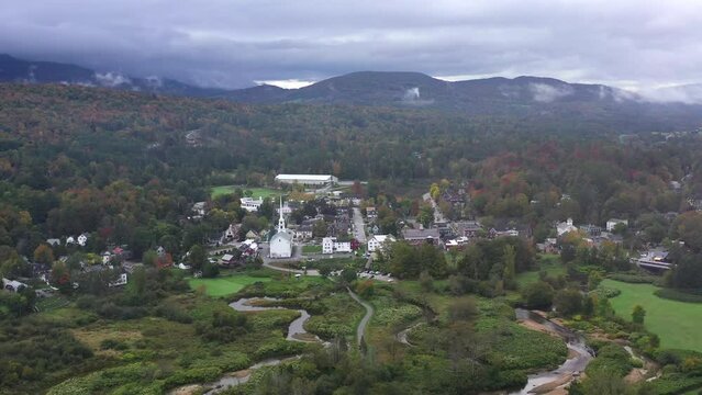 A beautiful view of a small town with a church, as you fly through clouds.