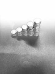 Coins arranged to show financial growth on a black background with space for text in grayscale