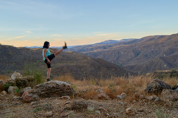 Young woman hiker in a canyon raising her leg celebrating.