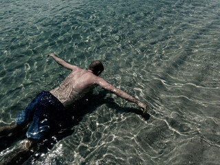 A man floats on the surface of the water, face down. Drowned in the ocean. Soft focus