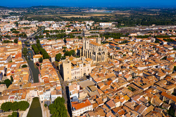 Scenic panoramic aerial view of residential areas of Narbonne with medieval Roman Catholic Cathedral on sunny summer day, France