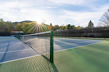 New blue outdoor tennis courts with white lines and red pickleball lines and background sun star.